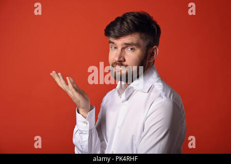 Doute penser homme charismatique barbu en faisant des gestes de la main en whirt à la chemise sur fond orange vif. Closeup portrait Banque D'Images