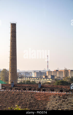 Ancienne cheminée en brique d'une usine abandonnée, à partir de la révolution industrielle, avec plus d'une zone industrielle moderne peut être vu dans l'arrière-plan, en Belg Banque D'Images