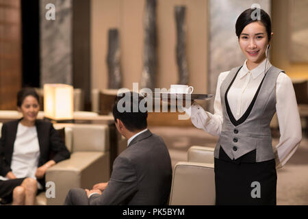 Cheerful young waitress serving coffee Banque D'Images