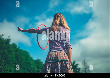 Une jeune femme est en train de tourner un hula hoop l'extérieur en été Banque D'Images