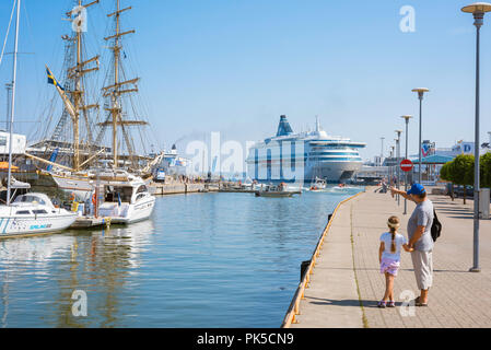Père fille, vue arrière d'un père et sa fille se tenant la main sur le quai du port de Tallinn en regardant les bateaux et les navires, de l'Estonie. Banque D'Images