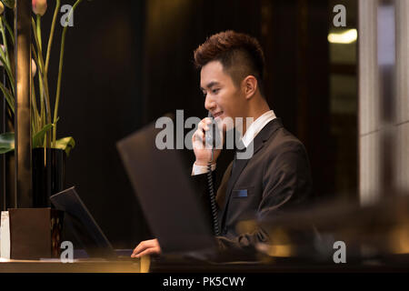 Cheerful hotel receptionist talking on the phone Banque D'Images