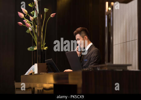Cheerful hotel receptionist talking on the phone Banque D'Images