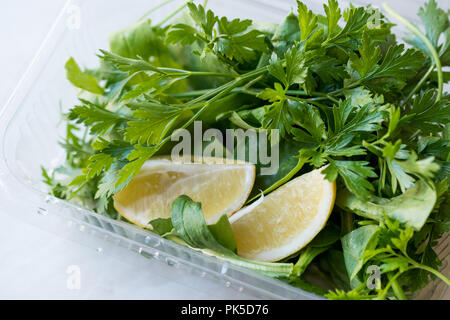 Le persil frais et à la roquette / Rucola avec feuilles de citron dans un contenant de plastique. L'alimentation biologique. Banque D'Images