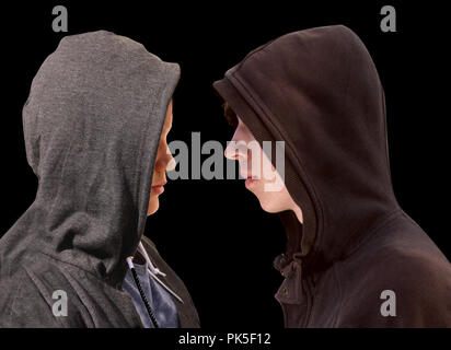 Deux adolescents en difficulté avec capuche noir debout en face de l'autre en profil isolé sur fond noir Banque D'Images