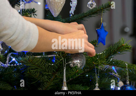 L'arbre de Noël décoré par une jeune fille aux cheveux rouges. Bleu et argent décorations. Baubles, perles et de glaçons. Banque D'Images