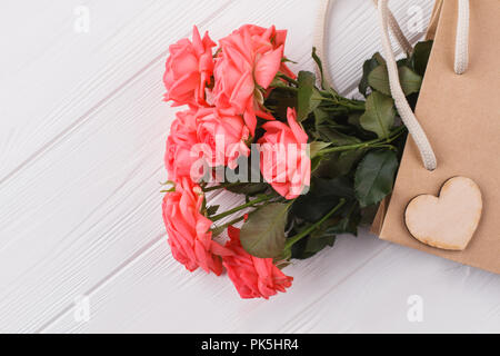 Roses roses dans votre panier. Close up. Fond de bois blanc. Banque D'Images