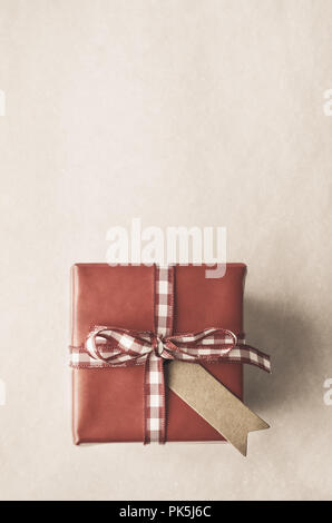 Coup de frais généraux boîte cadeau rouge avec étiquette de style parchemin de Vichy et vérifier ruban noué à l'archet. Retro vintage ou filtrée pour l'apparence. S COPIE Banque D'Images