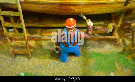 Mini figure miniature peinture travailleur un bateau au quai diorama Banque D'Images
