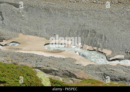 Un glacier stream traverse vieux ponts de neige dans les montagnes. Les pièces en haut à gauche du glacier peut être vu Banque D'Images