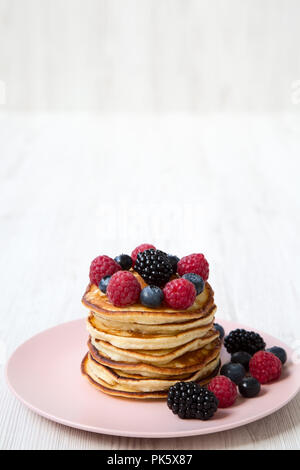 Crêpes aux fruits rouges sur une plaque en bois blanc, rose sur la surface, vue de côté. L'espace pour le texte. Banque D'Images