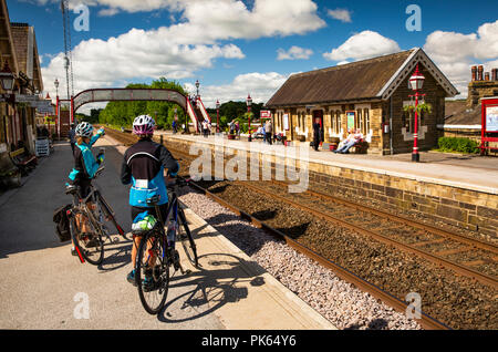 UK, Yorkshire, régler, les cyclistes sur la plate-forme de la gare en attente de s'installer à Carlisle Railway Line train Banque D'Images