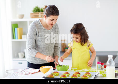 Happy mother and daughter baking muffins à la maison Banque D'Images