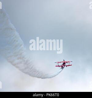 Un Pitts Special S2S traces biplan un chemin à travers un assombrissement sky Banque D'Images