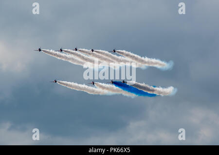 Un nuage de fumée bleu solitaire contraste avec l'épaisse fumée blanche des huit autres flèches rouges jets Hawk Banque D'Images