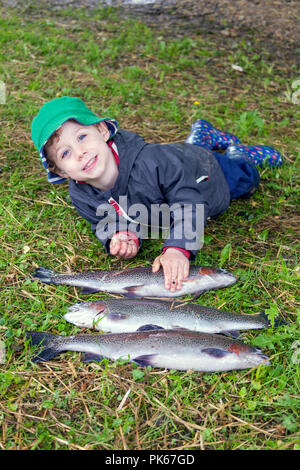 Quatre ans avec ses trois grosses truites arc-en-ciel le poisson, Meon Springs pêche à l'omble, East Meon, Hampshire, Angleterre, Royaume-Uni. Banque D'Images