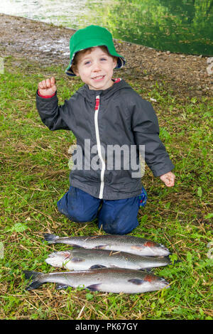 Quatre ans avec ses trois grosses truites arc-en-ciel le poisson, Meon Springs pêche à l'omble, East Meon, Hampshire, Angleterre, Royaume-Uni. Banque D'Images