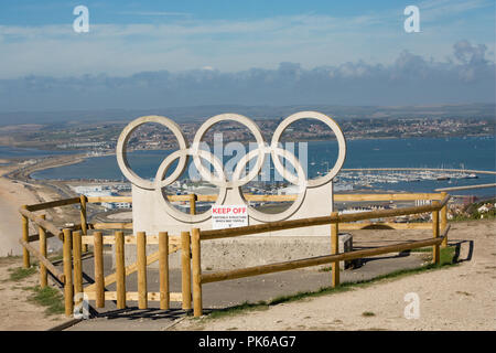 Une sculpture de pierre les anneaux olympiques sur l'Île de Portland dans un contexte de Portland Harbour. Les bagues ont été sculptés pour célébrer et Weymouth Banque D'Images