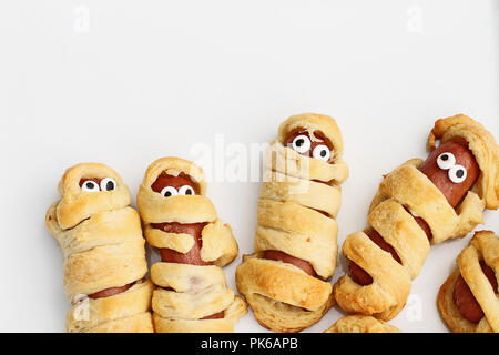 Fun food for kids. Maman Halloween hot-dogs. Rouleaux de saucisses enveloppées dans un croissant pour ressembler à des momies, sur une assiette. Alternative à la sucrerie. Banque D'Images