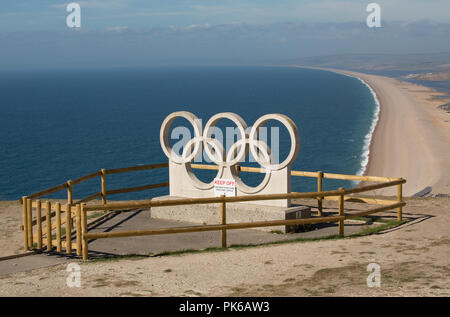 Une sculpture de pierre les anneaux olympiques sur l'Île de Portland, sur fond de plage de Chesil. Les bagues ont été sculptés pour célébrer Weymouth et por Banque D'Images