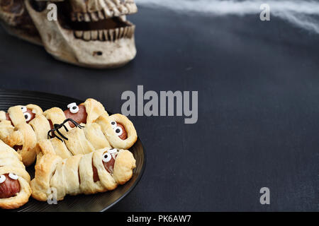 Fun food for kids. Maman Halloween hot-dogs. Rouleaux de saucisses enveloppées dans un croissant pour ressembler à des momies, sur une assiette. Alternative à la sucrerie. Banque D'Images