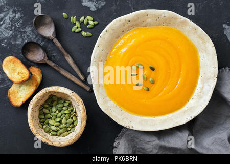 Crème de potiron soupe avec du pain grillé et des graines sur un fond sombre. Vue de dessus, les frais généraux, de mise à plat.