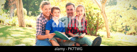 Lire un livre de la famille dans le parc par une journée ensoleillée Banque D'Images