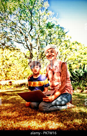 Grand-mère et petit-fils using laptop in the park Banque D'Images