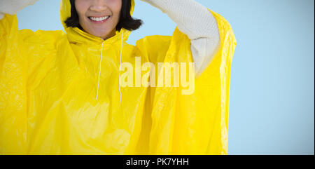 Image composite de femme portant imperméable jaune contre fond blanc Banque D'Images