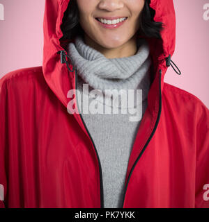 Portrait of woman in hooded jacket standing against white background Banque D'Images