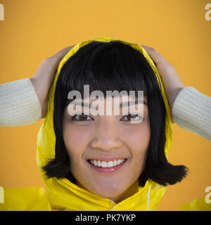 Image composite de femme portant imperméable jaune contre fond blanc Banque D'Images