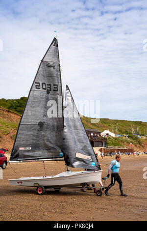 Royaume-uni, Angleterre, dans le Yorkshire, Filey, plage, RS200 succès racing canot rally, l'homme tirant à l'eau bateau Banque D'Images