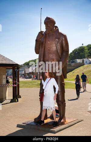 Royaume-uni, Angleterre, dans le Yorkshire, Filey, promenade, une marée haute en bref wellies pêcheur acier sculpture par Ray Lonsdale, woman posing for souvenir photograp Banque D'Images