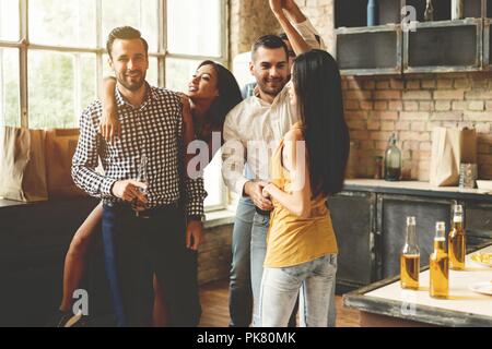 Profiter de la fête avec ses meilleurs amis. Cheerful young people dancing et boire tout en profitant d'accueil de travail sur la cuisine. Banque D'Images