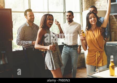 Profiter de la fête avec ses meilleurs amis. Cheerful young people dancing et boire tout en profitant d'accueil de travail sur la cuisine. Banque D'Images