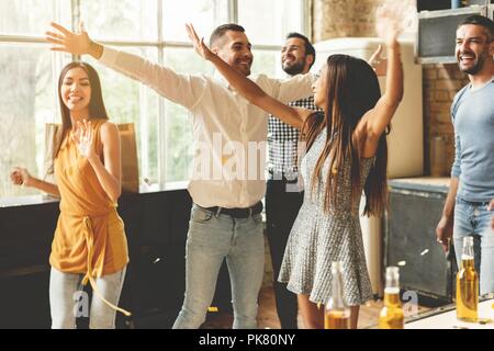 Profiter de la fête avec ses meilleurs amis. Cheerful young people dancing et boire tout en profitant d'accueil de travail sur la cuisine. Banque D'Images