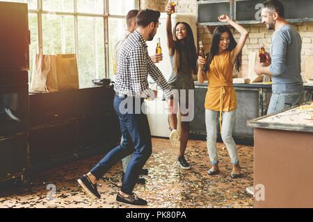 Profiter de la fête avec ses meilleurs amis. Cheerful young people dancing et boire tout en profitant d'accueil de travail sur la cuisine. Banque D'Images