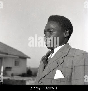 Années 1950, historique, un Potrait d'un jeune homme habillé ougandais portant un veston et une cravate à motifs contrôle et avec un handerchief dans la poche avant. Banque D'Images
