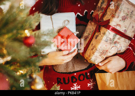 De nombreux cadeaux de Noël dans les mains d'or à l'arbre de Noël avec de belles lumières dans la salle des fêtes de l'hiver. moments atmosphériques. saisons greetin Banque D'Images