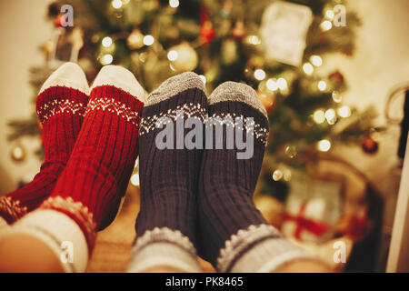 Chaussettes de fête élégante sur deux jambes sur fond de golden belle arbre de Noël avec les lumières dans la salle de fête de famille. vous détendre le temps d'hiver douillet holi. Banque D'Images