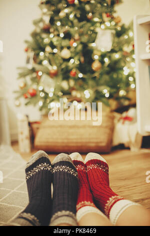 Les jambes de la famille dans l'élégant quartier de chaussettes de fête sur fond de golden beau sapin de Noël avec des lumières de Noël prix. Détendez-vous le temps ensemble d'hiver douillet. ho Banque D'Images