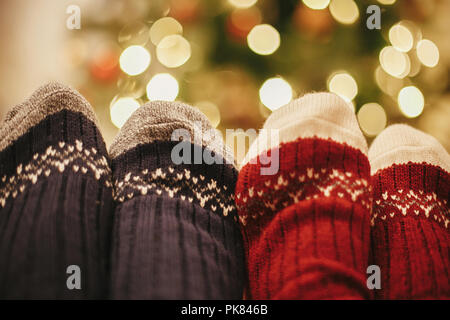 Les jambes de la famille dans l'élégant quartier de chaussettes de fête sur fond de golden beau sapin de Noël avec des lumières de Noël prix. Détendez-vous le temps ensemble d'hiver douillet. ho Banque D'Images