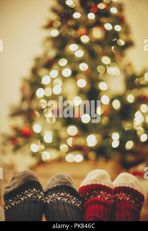 Chaussettes de fête élégante sur deux jambes sur fond de golden belle arbre de Noël avec les lumières dans la salle de fête de famille. vous détendre le temps d'hiver douillet holi. Banque D'Images