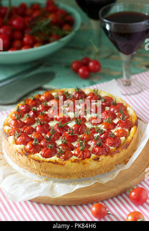 Tart, tarte ou gâteau au fromage avec du fromage cottage et tomates, servi avec du vin rouge sur un fond de bois. Focus sélectif. Banque D'Images