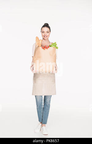 Woman in apron holding paquet papier plein de nourriture isolated on white Banque D'Images