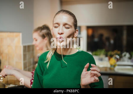 Jeune femme se posant pour l'appareil photo avec des spaghetti de traîner sa bouche. Banque D'Images
