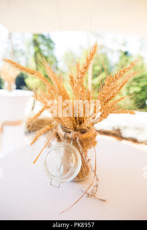 Les épis de blé séchées en pot verre conserver en décoration de mariage rustique chic minable Banque D'Images