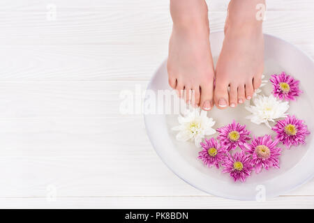 Vue partielle de barefoot woman receiving baignoire pour ongles fleurs en instituts de beauté Banque D'Images