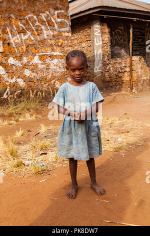 ALU - KINONDO, KENYA - Mars 01, 2018 : belle petite fille kenyane est debout devant sa maison et looking at camera Banque D'Images