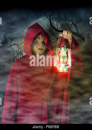 Costume halloween homme masqué portant un habit rouge habit sectaire dans un cimetière lors d'une nuit brumeuse pleine lune monster démon Banque D'Images